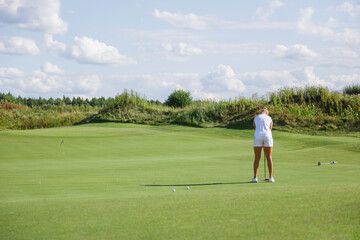 Beautiful tanned golfer girl on the golf course.