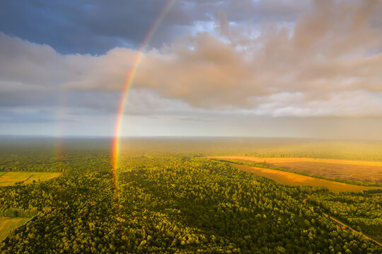 Half rainbow over green forest.