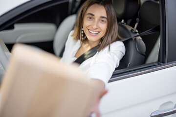 Obraz na płótnie Canvas Woman receiving a parcel through the vehicle window on the go