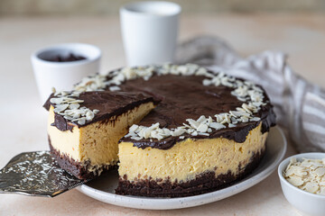 Delicious creamy cheesecake decorated with chocolate glaze and almond, light concrete background. No bake mousse dessert.