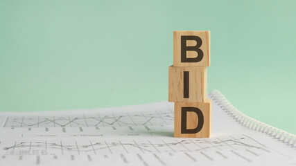 BID - on wooden cubes the inscription is a proposal. concept on cubes and diagrams on a gray...