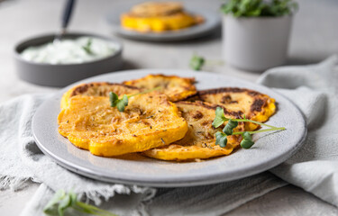 Fried patisson or yellow zucchini with sauce and micro greens, grey concrete background.