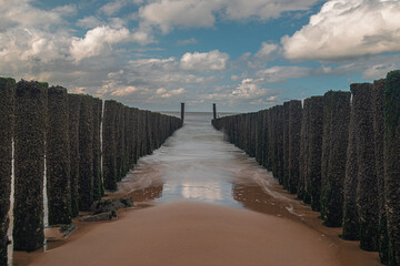 Long exposure of the Dutch coastline with the water breakers during low tide of the North sea with a dramatic sky