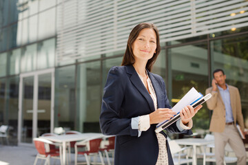 Businesswoman carrying folders outdoors