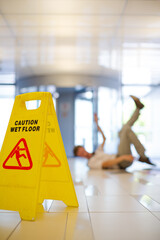 Businessman slipping on wet office floor