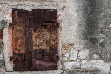 rusty metal window shutters in an old wall