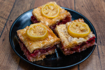 Homemade sweet pastry made of layers of filo filled with chopped nuts, cherry and sweetened and held together with syrup or honey.