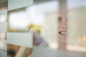 Businessman talking on cell phone at office window