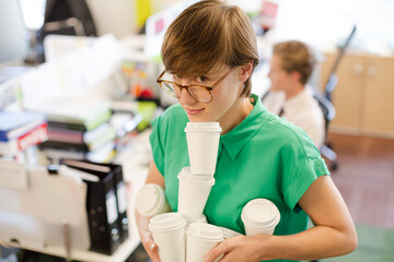 Businesswoman balancing empty coffee cups