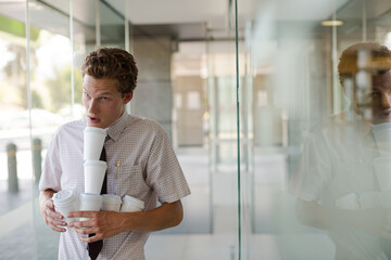 Businesswoman balancing coffee cups in office