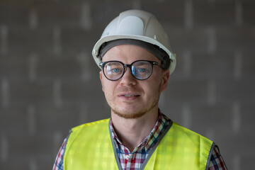 portrait of a male engineer at work, a European male designer or architect at the site, the work of a qualified and confident engineer in glasses and white helmet, engineering on large construction