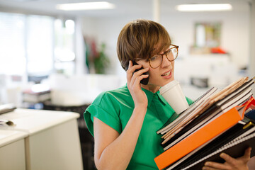 Businesswoman with folders talking on cell phone