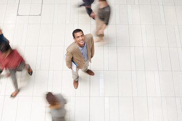 Businessman smiling in busy office hallway