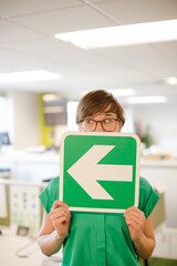 Businesswoman holding arrow sign in office