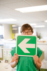 Businesswoman holding arrow sign in office
