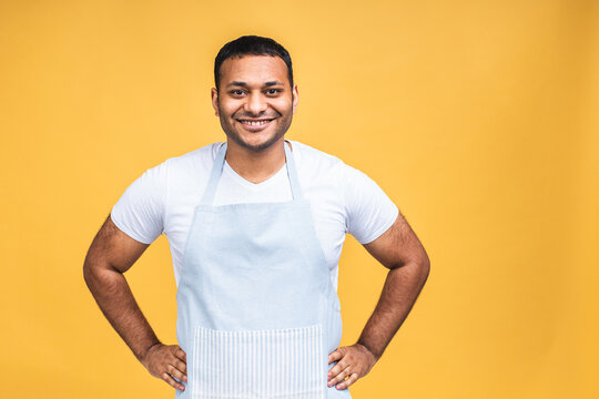 Young african american indian black cooker man wearing apron isolated over yellow background.
