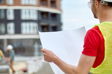 Experienced male engineer in a hardhat studying a building plan