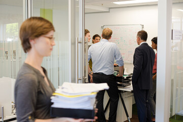Obraz premium Businesswoman carrying pile of documents in office