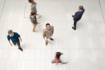 Businessman smiling in busy office hallway