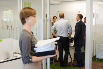 Obraz premium Businesswoman carrying pile of documents in office