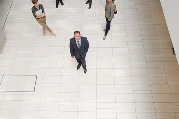 Businessman smiling in busy office hallway