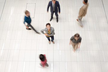 Businesswoman standing in busy office hallway