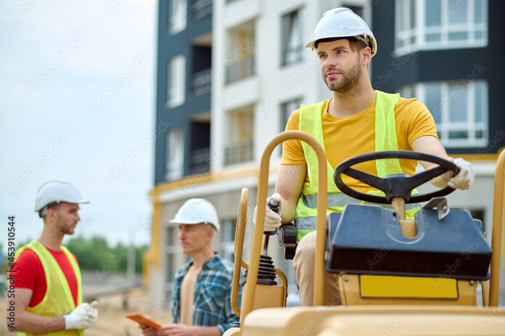 Wall mural Serene construction worker and his two coworkers outdoors