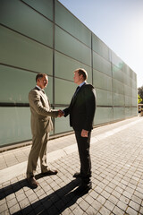 Businessmen shaking hands on city street