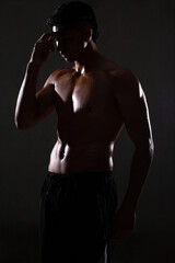 Naklejka na ściany i meble handsome looking muscular latin man posing shirtless on a dark background