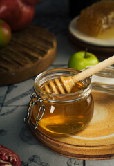 Glass jar with fresh honey, honey spoon, apple and pomegranate. Concept Jewish New Year Happy holiday Rosh Hashanah. layout of traditional symbols. View from above. Shana Tova