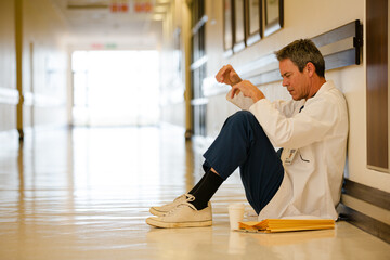 Doctor sitting on floor in hospital corridor