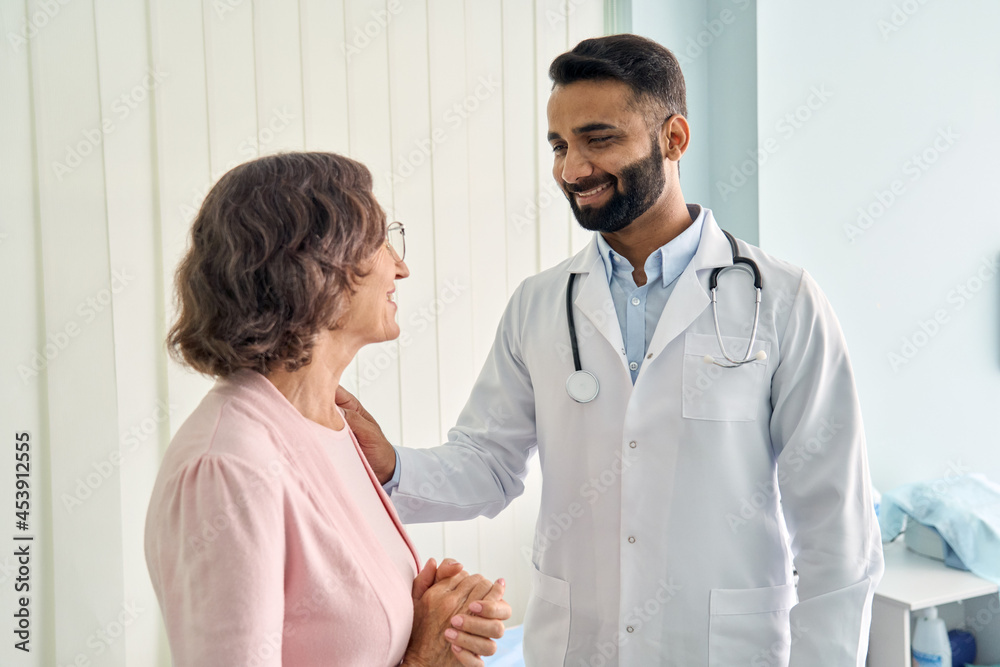 Wall mural happy young indian doctor therapist in white coat has appointment consulting supporting putting hand