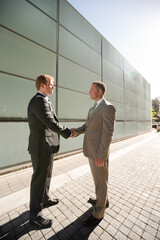 Businessmen shaking hands on city street