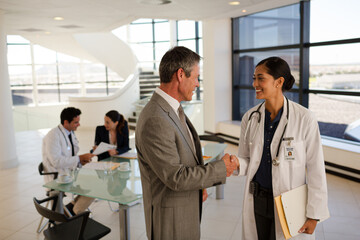 Obraz premium Portrait of smiling doctor drinking coffee on floor in hospital corridor