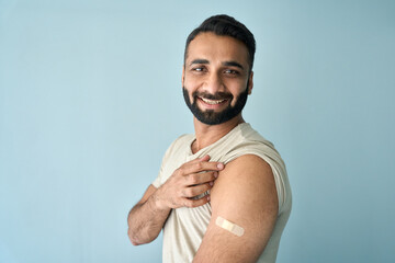 Cheerful happy smiling Indian man standing with plaster on shoulder after getting covid 19 vaccine...