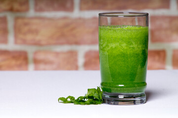 green juice with celery leaf in a glass on white table, healthy eating concept
