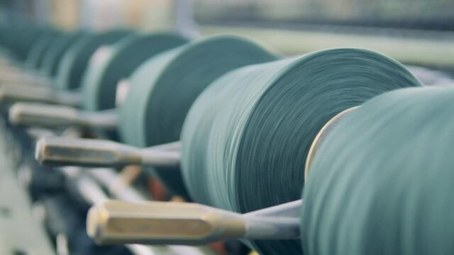 Thread spools are rotating in the textile machinery in a close up