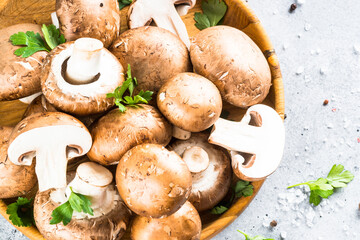 Raw mushrooms Champignon in wooden bowl with spices. Top view at black background.