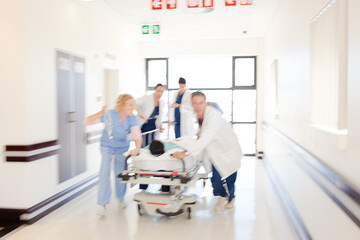 Obraz premium Doctors rushing patient on gurney in hospital corridor