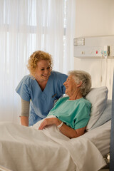 Obraz premium Nurse and senior patient talking in hospital room