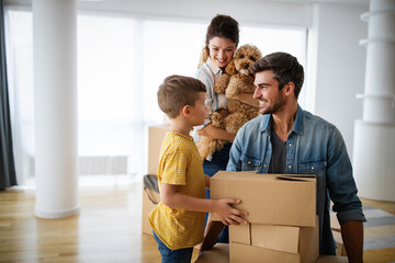 Happy family with children moving with boxes in a new apartment house.