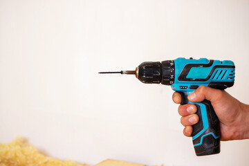 Hand with cordless screwdriver and drill isolated on white background. Twists screws into the board.