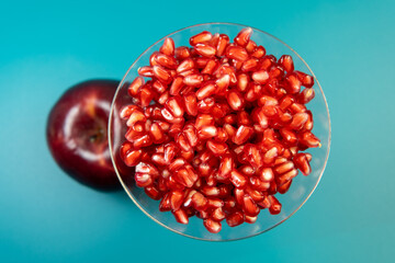 Healthy pomegranate seeds in cocktail glass with apple on dark background