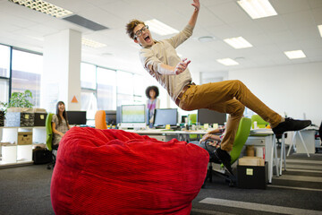 Businessman jumping into beanbag chair in office
