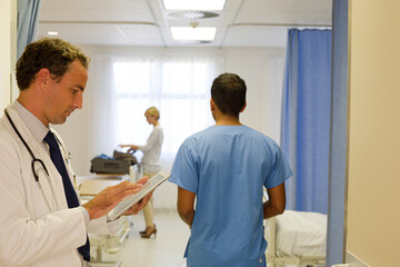 Fototapeta premium Doctor reading clipboard in hospital room