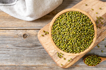 Green mung beans in a bowl on a gray wooden table. Legume plant for a healthy diet closeup