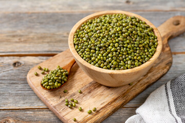 Green mung beans in a bowl on a gray wooden table. Legume plant for a healthy diet closeup