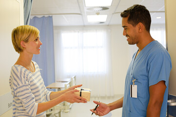 Patient giving nurse gift in hospital