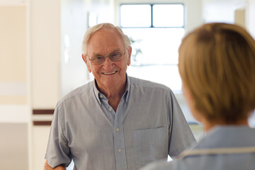 Older patient and nurse shaking hands in hospital