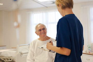 Nurse and older patient talking in hospital room